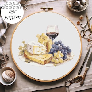 Könnte beinhalten: Ein Kreuzstichmuster mit einem Glas Rotwein, einem Teller Käse und Trauben. Der Käse ist ein runder Brie mit einer weißen Rinde und die Trauben sind grün und lila.