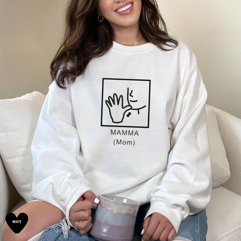 May include: White sweatshirt with a black graphic of a hand signing "mamma" with the text "Mamma (Mom)" underneath.