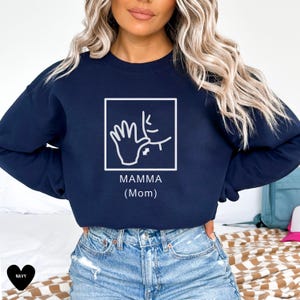 May include: Navy blue sweatshirt with a white graphic of the American Sign Language sign for "mamma" (mom). The graphic is inside a white square with the text "MAMMA (Mom)" below it.