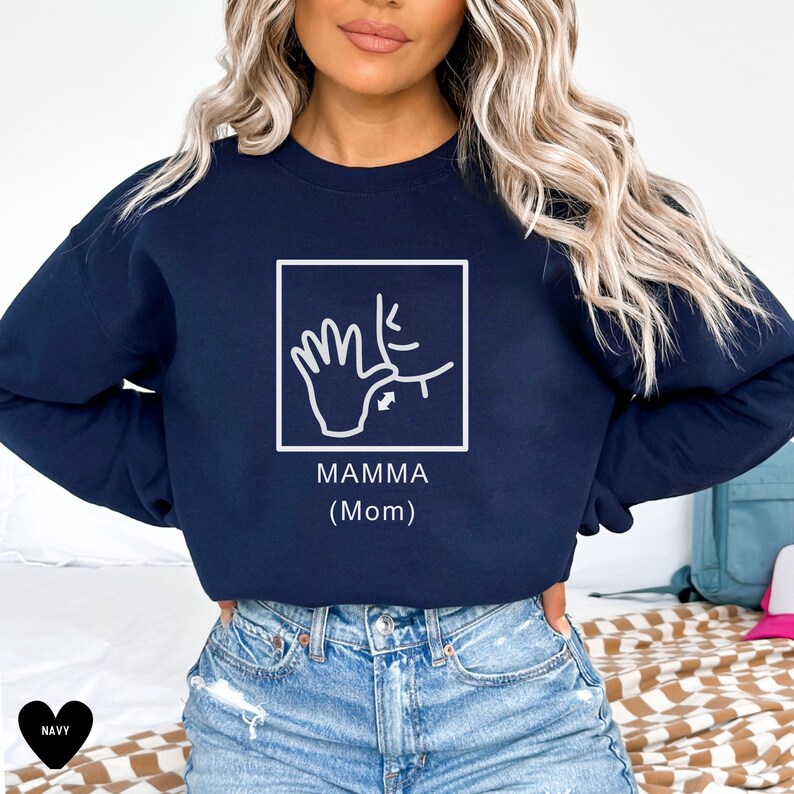 May include: Navy blue sweatshirt with a white graphic of the American Sign Language sign for "mamma" (mom). The graphic is inside a white square with the text "MAMMA (Mom)" below it.