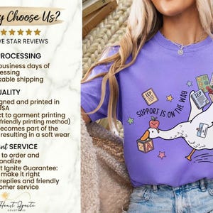 May include: A violet-colored t-shirt features a cartoon goose carrying school supplies and the text "SUPPORT IS ON THE WAY." The design includes stars, an apple, and the letters "IEP" on cards. The shirt also has the text "Why Choose Us?" and "FIVE STAR REVIEWS."