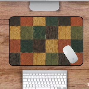 Puede incluir: Alfombrilla de ratón rectangular con un diseño de patchwork con cuadrados de hojas y texturas de madera en tonos naranja, verde y marrón. La alfombrilla mide 30,5 x 45,7 cm. Un ratón blanco descansa sobre la alfombrilla.