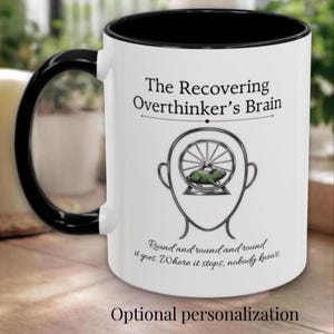 Może przedstawiać: Biały ceramiczny kubek z czarnym wnętrzem i uchwytem. Kubek zawiera napis "The Recovering Overthinker's Brain" oraz grafikę chomika w kole w kształcie głowy. Dodatkowy tekst brzmi "Round and round it goes. Where it stops, nobody knows."