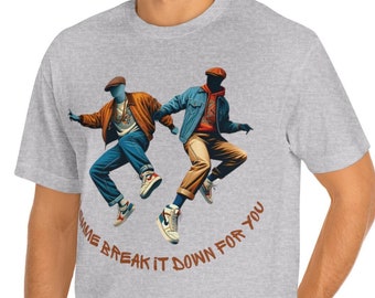 Puede incluir: Una camiseta gris jaspeada con un gráfico de dos hombres con ropa azul y naranja saltando en el aire. El texto "Come Break It Down For You" está impreso en naranja debajo del gráfico.