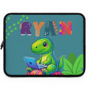 Może przedstawiać: Niebieska torba na laptopa z zielonym dinozaurem trzymającym laptopa. Dinozaur siedzi na kolorowej poduszce. Imię "RYAN" jest napisane kolorowymi literami nad dinozaurem.