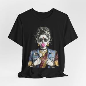 May include: Black t-shirt featuring a graphic of a woman with sunglasses blowing a bubblegum bubble. The woman is wearing a denim jacket, jewelry, and a traditional Indian sari. The illustration is in black and white with pops of color.