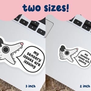 May include: Two stickers featuring a cartoon opossum with the text "my sensory issues are issuing" in a speech bubble. The stickers are available in 3-inch and 2-inch sizes. The opossum is gray and white with black accents.