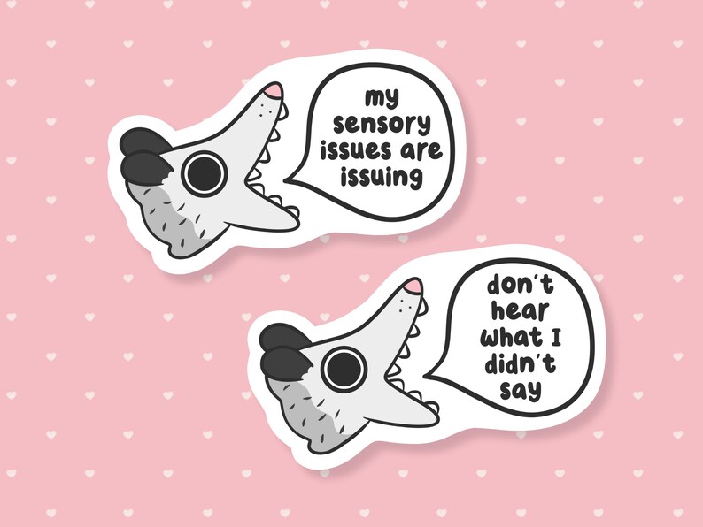 May include: Two white stickers with a cartoon alligator design. One sticker has the text "my sensory issues are issuing" in a speech bubble. The other sticker says "don't hear what I didn't say".