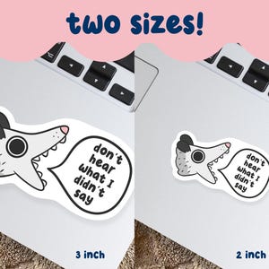 May include: Two stickers featuring a cartoon opossum with the text "don't hear what I didn't say." One sticker is 3 inches, the other is 2 inches. The opossum is gray, white, and black, with a pink nose and a speech bubble.
