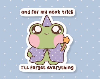 May include: A cute cartoon frog wearing a wizard hat and cape, holding a star-shaped wand. The frog is green with pink cheeks and large eyes. Text reads "and for my next trick I'll forget everything."