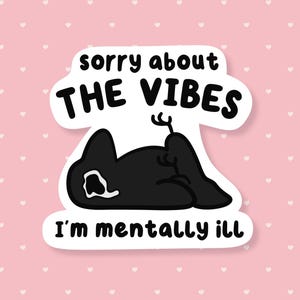 May include: A sticker with a black cat illustration, lying down with its tail up. The text reads "sorry about THE VIBES I'm mentally ill" in a speech bubble. The background is pink with white hearts.