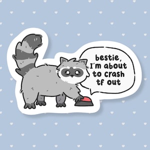 May include: A sticker featuring a cartoon raccoon with a grey body, black mask, and striped tail. The raccoon is reaching for a red button. A speech bubble says, "bestie, I'm about to crash tf out."