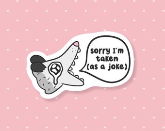Op de afbeelding: Een sticker met een cartoon opossum met een bedroefde uitdrukking. De opossum is grijs en wit met zwarte oren en een roze neus. Een tekstballon zegt "sorry I'm taken (as a joke)". De achtergrond is roze met witte hartjes.