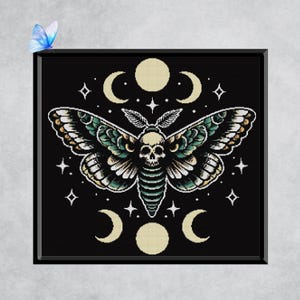 May include: Black framed artwork depicting a moth with a skull design, surrounded by crescent moons, stars, and circles. The moth has green, white, and black wings. A blue butterfly is in the upper left corner.
