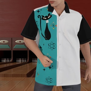 May include: A teal blue, white and black bowling shirt with a retro atomic age design. The shirt features a black cat with a white collar and a bow, atomic symbols and stars.