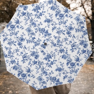 May include: A white umbrella with a blue floral pattern. The flowers are stylised and resemble a toile pattern.