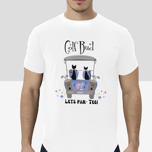 May include: White t-shirt featuring a graphic of two black cats riding in a golf cart. The text "Golf Bud" is above the image and "Lets Par-Tee!" is below the image.