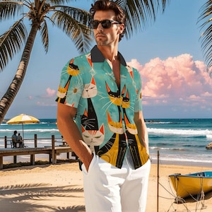May include: A short-sleeved button-down shirt with a light blue background and a repeating pattern of stylized black, orange, and white cats. The shirt has a black collar and is worn with white pants. The scene is set on a beach with palm trees and a yellow boat.