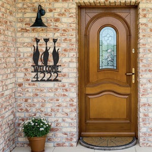 Puede incluir: Placa de número de casa de metal negro con tres gatos negros y la palabra "WELCOME" sobre el número "4222".