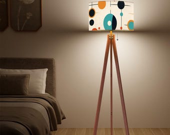 May include: A tripod floor lamp with a white lampshade featuring a geometric pattern of circles and lines in shades of blue, orange, and black.