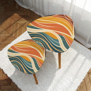 May include: Two small, mid-century modern accent tables. The tabletop features a colorful abstract design with orange, yellow, and teal wave patterns. The tables have three wooden legs and are placed on a white shag rug.