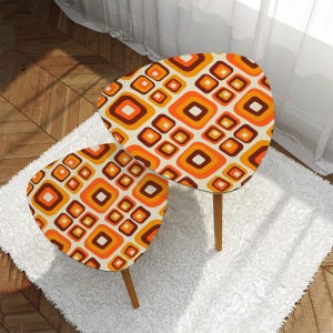 Peut inclure: Deux tables d'appoint rétro avec un motif géométrique orange, marron et crème. Les tables ont une forme triangulaire arrondie et des pieds en bois. Elles sont posées sur un tapis en fausse fourrure blanc. Mesurent environ 60 cm de long.