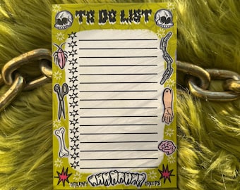 May include: A yellow to-do list notepad with a skull, bones, scissors, a cockroach, a chain, a hand, and a brain on the border. The text "TO DO LIST" is at the top of the notepad. The bottom of the notepad says "DREAMY" and "CREEPS".