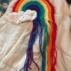 May include: A crocheted rainbow with a white cloud and rainbow colored yarn tassels.