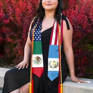 Puede incluir: Un vestido negro con estolas de graduaci&oacute;n con las banderas de Estados Unidos, M&eacute;xico y Guatemala. Las estolas tienen borlas doradas y rojas. El fondo es un arbusto rojo vibrante.