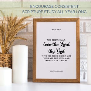 May include: A framed print with the text "love the Lord thy God" in a decorative font. The frame is brown, and the background is white. The print is displayed with candles and wheat stalks.
