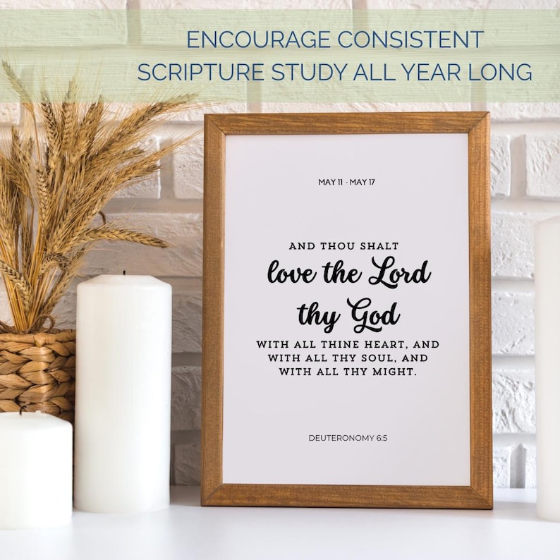 May include: A framed print with the text "love the Lord thy God" in a decorative font. The frame is brown, and the background is white. The print is displayed with candles and wheat stalks.