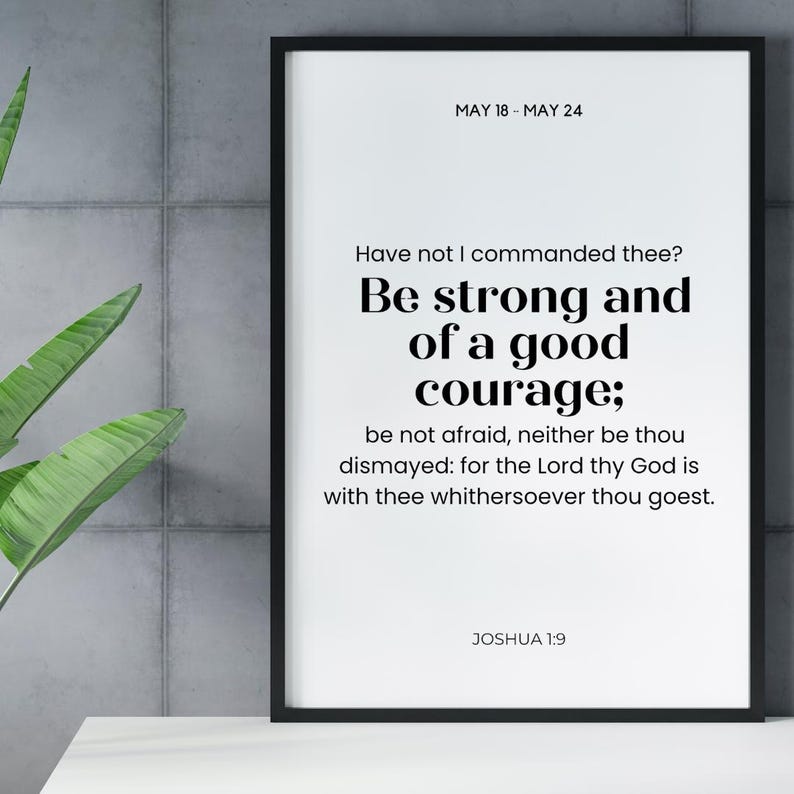May include: A framed print with a black border features the text "Be strong and of a good courage;" from Joshua 1:9. The top of the print reads "MAY 18 - MAY 24". The background is white, and the text is in black.