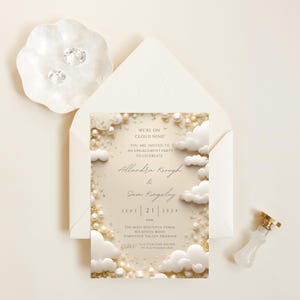 Peut inclure: Une invitation de fête de fiançailles blanche et dorée avec un motif de nuage et de perle. L'invitation indique "We're on Cloud Nine!" et comprend les noms "Allandra Keough & Sam Kingsley" et la date "Sept 21, 2024".