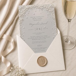 Puede incluir: Una tarjeta de invitaci&oacute;n rectangular para una despedida de soltera con fondo gris claro y un borde de perlas blancas. El texto dice: You are invited to a bridal shower honouring Magnolia Jewel, Sept 26 2026, at two o'clock in the afternoon.