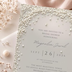 Puede incluir: Una tarjeta de invitaci&oacute;n para una despedida de soltera con fondo gris claro y un borde decorativo de perlas blancas y cristales transparentes. El texto dice: YOU ARE INVITED TO A BRIDAL SHOWER HONOURING Magnolia Jewel SEPT 26 2026 AT TWO O'CLOCK.