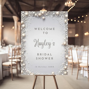 Puede incluir: Un cartel de bienvenida blanco con un borde de perlas y purpurina plateada. El cartel dice "Bienvenido al Shower Nupcial de Hayley 19 de octubre de 20XX".