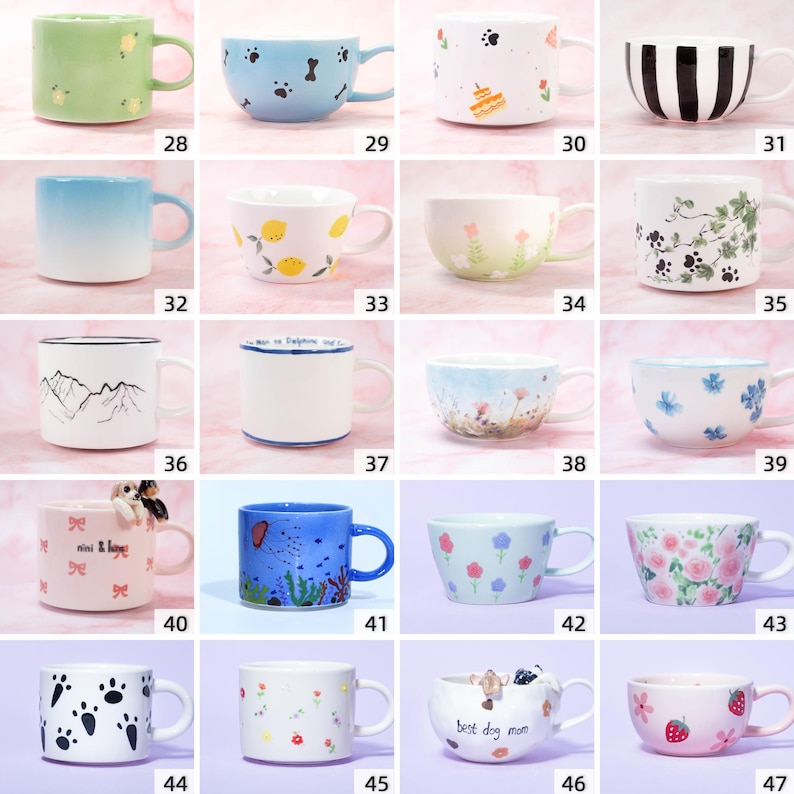 May include: A selection of ceramic mugs with diverse patterns. Features include a green mug with dots, a blue mug with paw prints, a white mug with a cake, and a black and white striped mug. Other mugs display floral, mountain, and dog-themed designs.