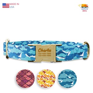 May include: Blue dog collar with a gold buckle and a personalized name tag that reads "Charlie" and a phone number. The collar features a repeating pattern of white clouds on a blue background. Three smaller circles show variations of the pattern in pink, orange, and blue.