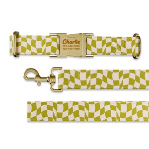 May include: A gold dog collar and leash set with a checkered pattern in green and white. The collar has a gold buckle with a personalized name tag that reads "Charlie" and a phone number.