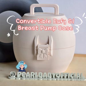 May include: A light pink Convertible Eufy S1 Breast Pump Case with a handle and bow-shaped clasp. The case is oval-shaped and has the text "Convertible Eufy S1 Breast Pump Case" in red. The case is designed to store a breast pump.