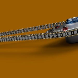 May include: A silver and black chain with gold accents wraps around a silver and white circular object with red and blue accents. The chain is connected to a smaller silver object.