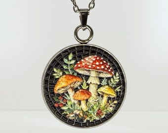 May include: A round silver-toned pendant necklace featuring a detailed embroidered scene of various mushrooms in shades of red, orange, and yellow, set against a dark, textured background with small green leaves and tiny red berries.