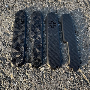 Könnte beinhalten: Vier schwarze Taschenmesser mit unterschiedlichen Mustern auf den Griffen. Die Muster umfassen ein geometrisches Design, ein Karbonfaser-Design und ein einfarbig schwarzes Design. Jedes Messer hat ein kleines Kreuz auf dem Griff.