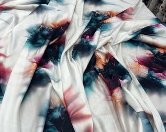 May include: White fabric with a vibrant, abstract floral pattern in shades of teal, orange, and magenta. The fabric is draped, showing folds and texture. The design resembles watercolor or ink art.