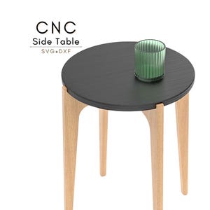 May include: A modern side table with a round, dark gray top and three light wood legs. A green glass candle holder sits on the table. The text "CNC Side Table SVG+DXF" is in the upper left corner.