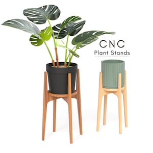 May include: Two wooden plant stands with a modern design. One stand holds a black pot with a large green plant, the other holds a light green pot. The stands have a mid-century modern style. The text "CNC Plant Stands" is visible.