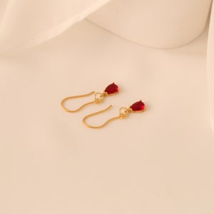 Peut inclure: Une paire de boucles d'oreilles en or avec des pierres rouges en forme de goutte.