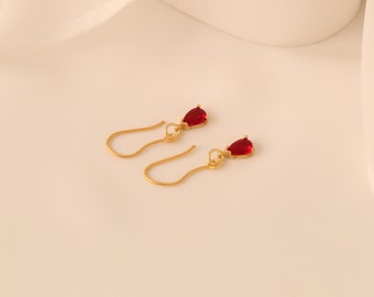 May include: A pair of gold earrings with red teardrop-shaped stones.