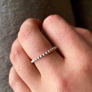 May include: A silver beaded ring on a finger.