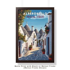 May include: A vintage travel poster featuring a colorful illustration of a street in Alberobello, Puglia, Italy. The street is lined with white buildings with conical roofs, and there is a bicycle parked on the side of the street.